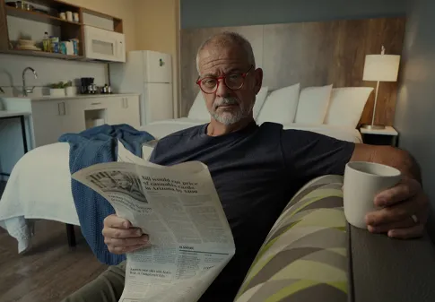 senior man lounging while reading newspaper